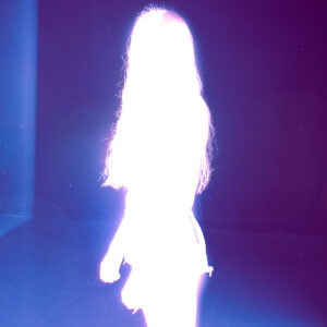 A purple image with a white glowing figure standing still.